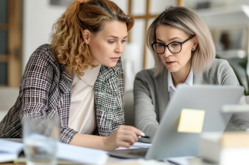 two women going over notes and looking at a laptop