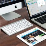 desk with tablet, laptop, and desktop on it